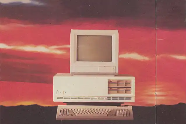 Ein Bild, das einen alten Computer vor einem Hintergrund mit einem Sonnenuntergang zeigt