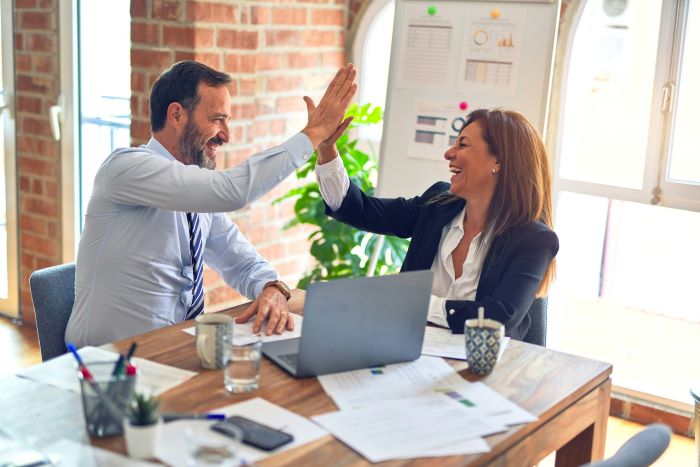 Zwei Personen im Büro geben sich gegenseitig ein High Five