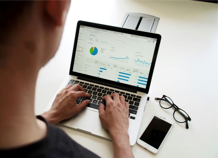 Datenanalyst, der am Computer sitzt und Diagramme analysiert