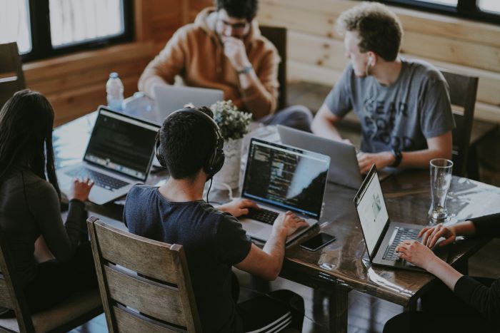 Eine Gruppe von Menschen, die in einem Büro vor Laptops sitzen