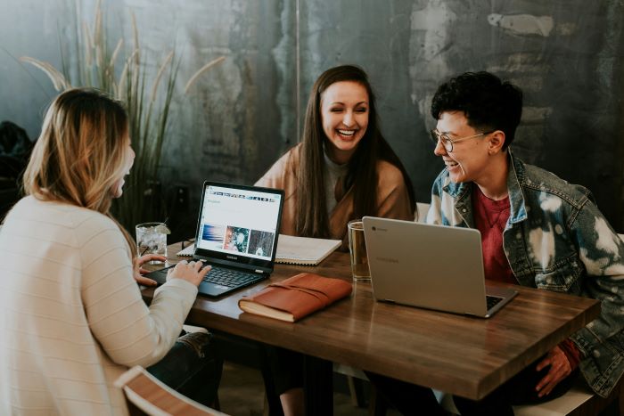 A group of people sitting around a table and working on laptops