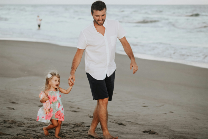 Photo showing a father with a daughter spending time on a beach.
